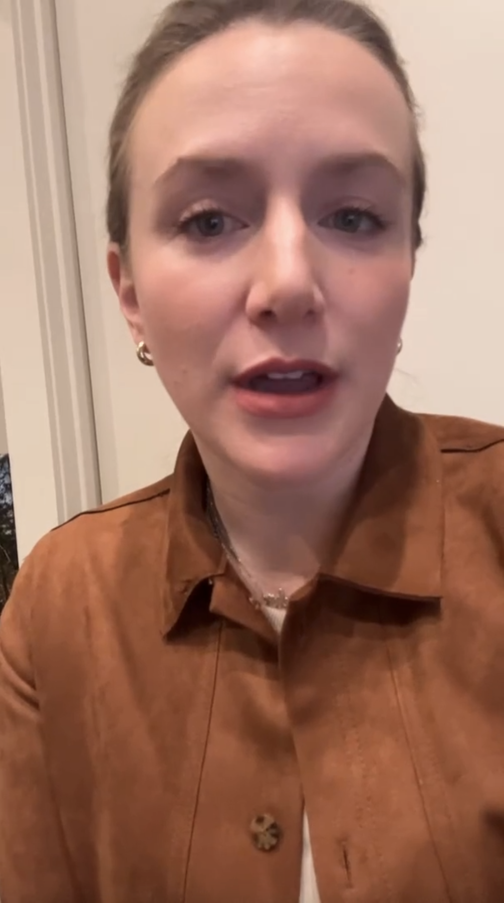 Professional portrait of a woman with light skin and light brown, pulled-back hair, wearing a brown jacket and small earrings. She faces the camera in a neutral indoor setting—featured on Loqal Marketing's website.